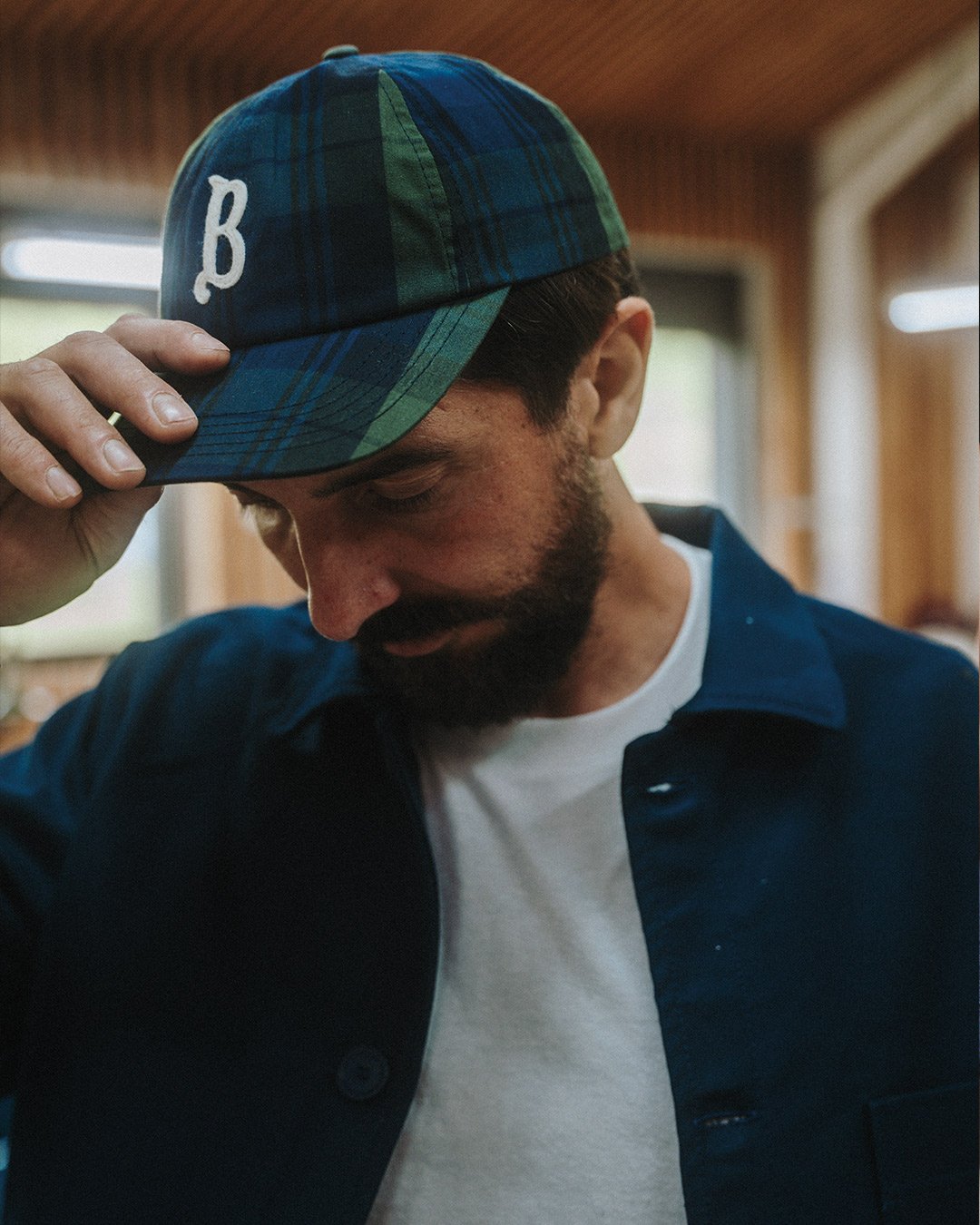 A man holds his tartan cap on his head