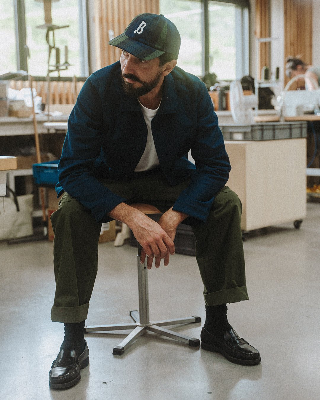 A man sits in the Bleu de Chauffe workshop and wears the "Gaspard" cap.