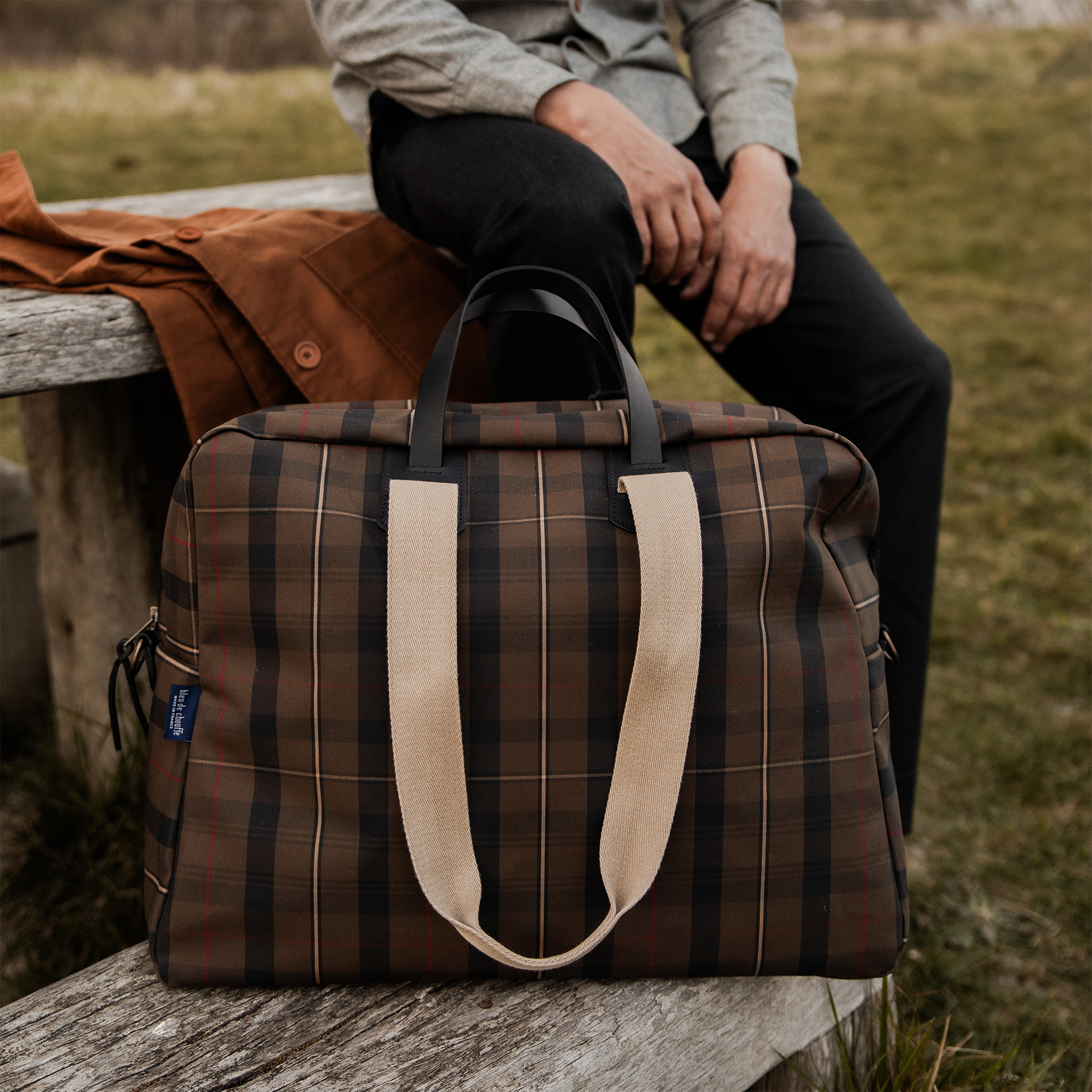 Sac voyage homme tartan posé sur une table en bois