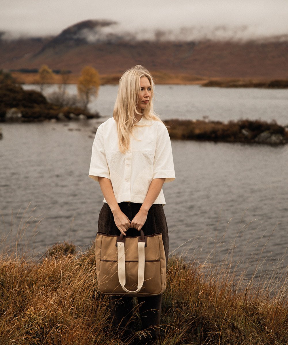 A woman in front of a lake wears the Meline women's tote bag