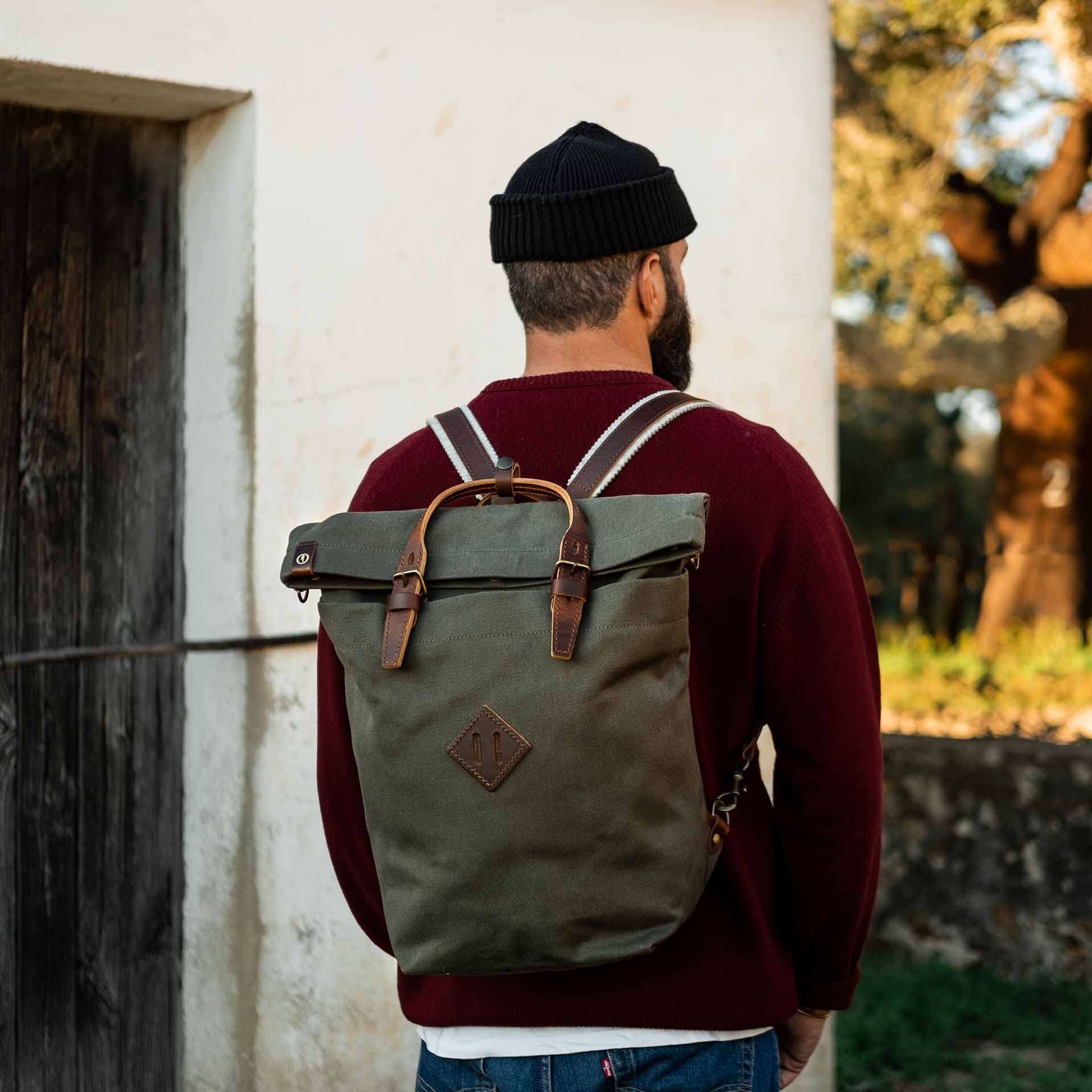 A man carries Woody's backpack on his back outdoors.