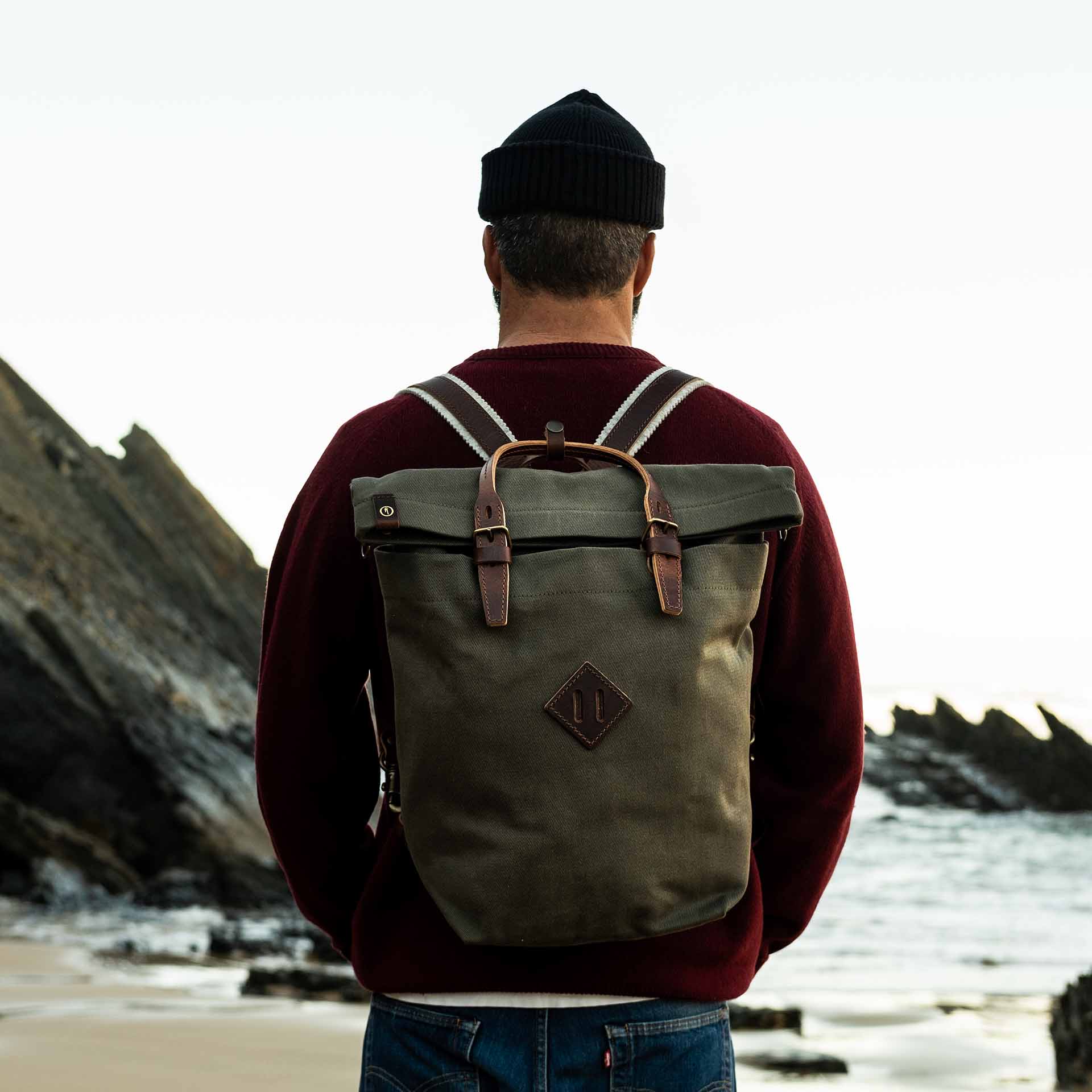 A man carries Woody's backpack on a beach