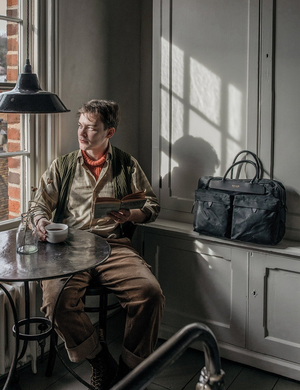 A man drinking coffee next to his Helios business bag