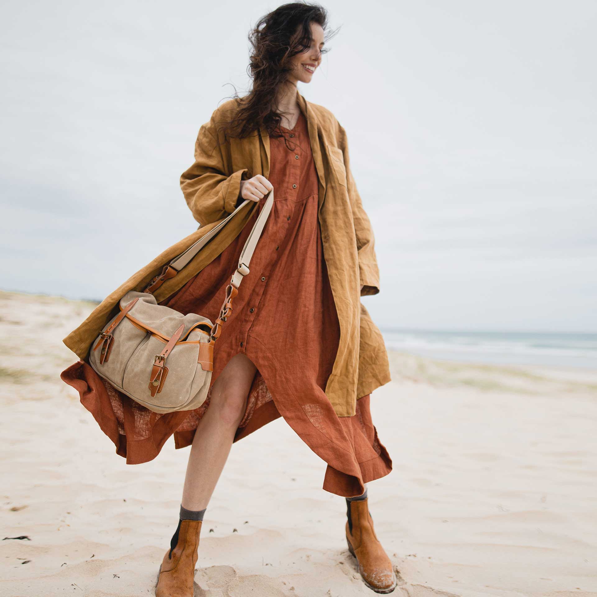 Une femme sur la plage tient un sac musette par sa bandoulière