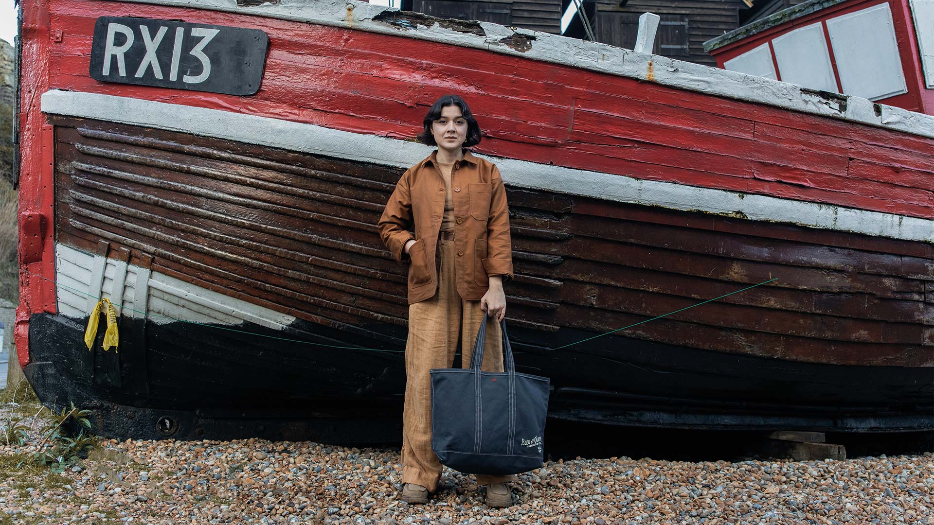 A woman wears a Labor Day shopping bag in front of a shipwreck