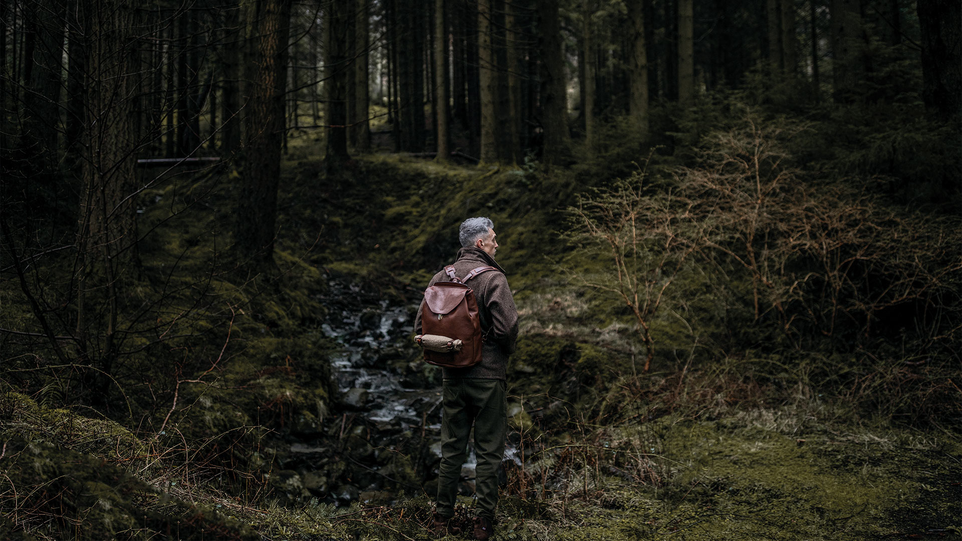 A man in the forest carrying the sable leather backpack