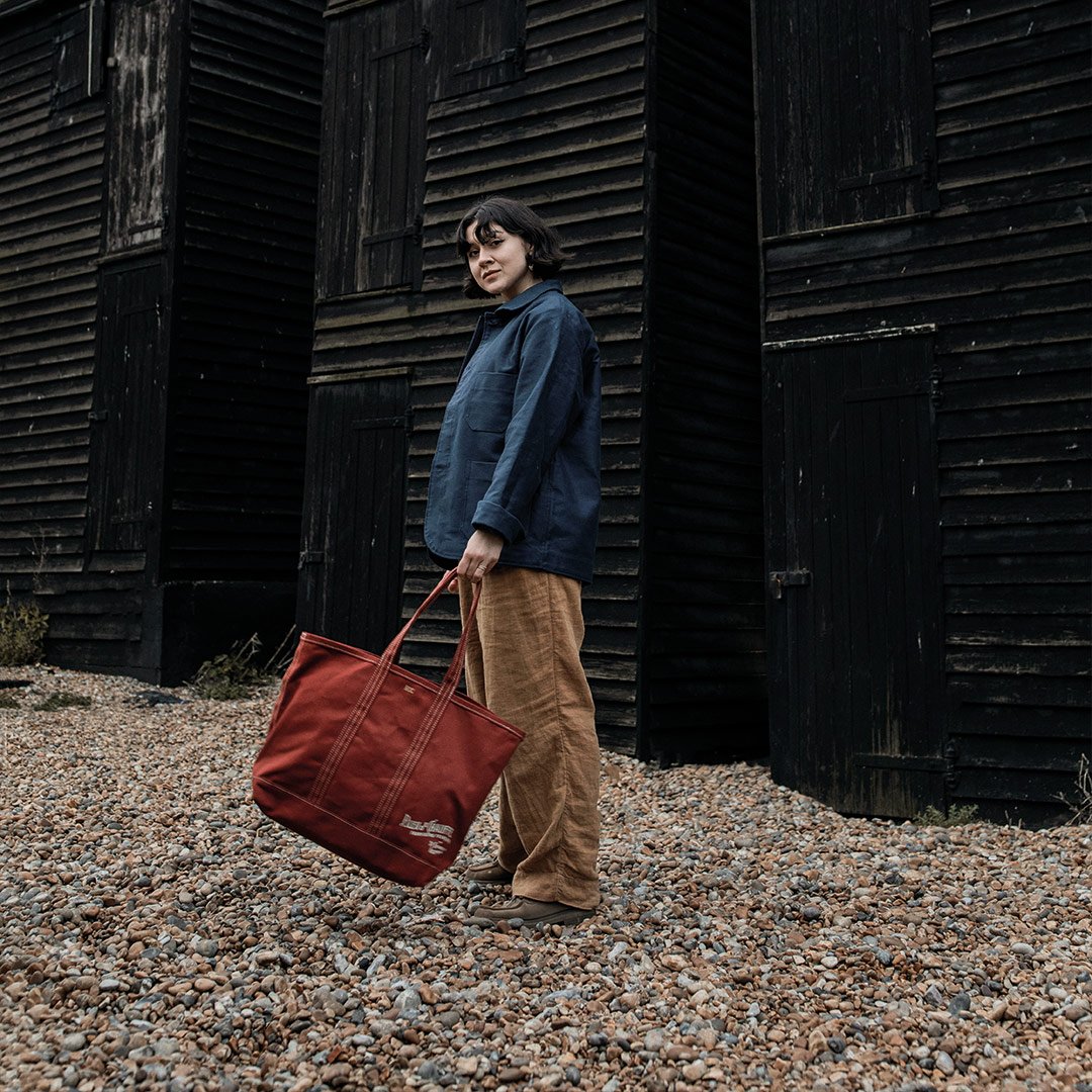 A woman carries a red canvas shopping bag