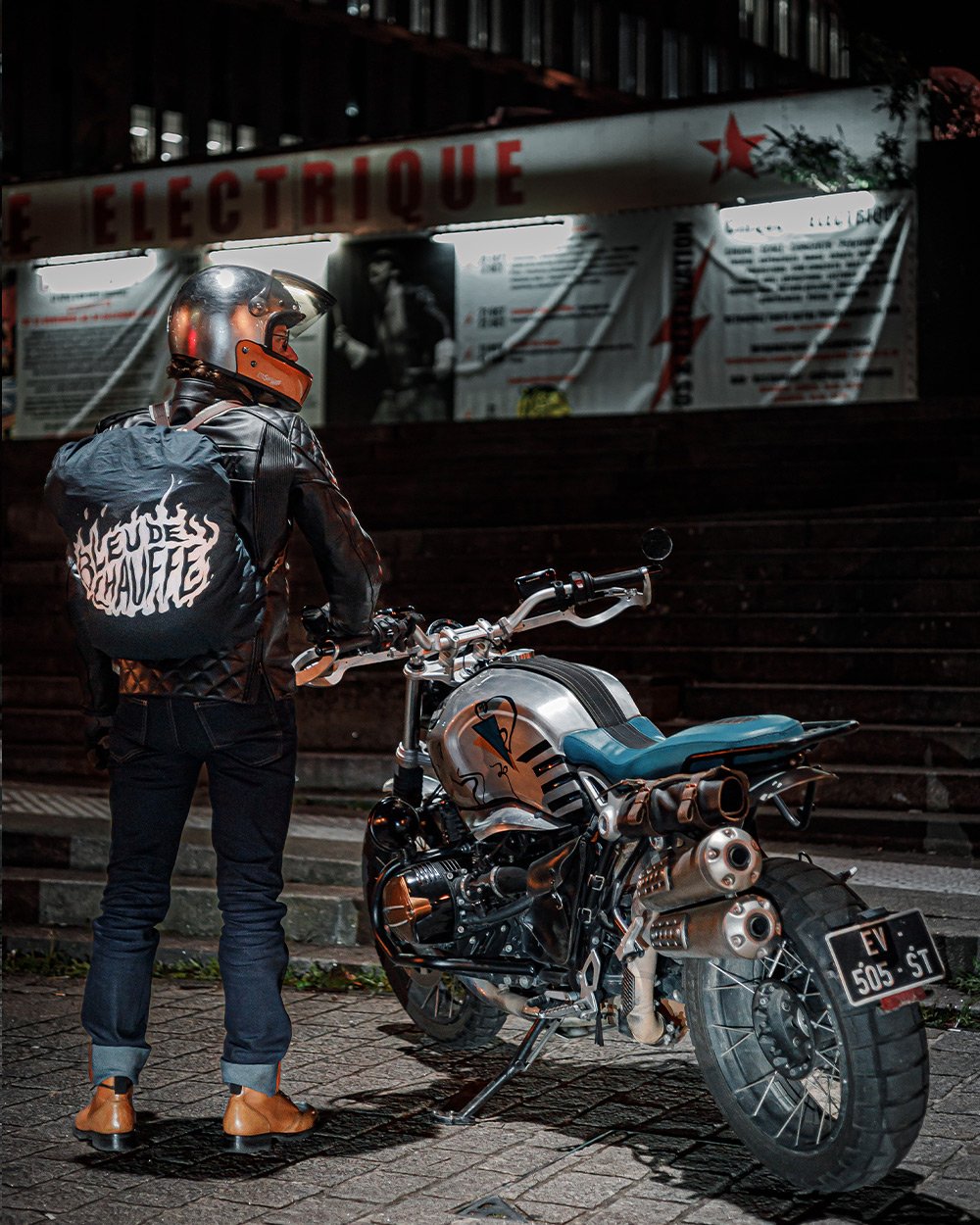 Un homme de dos avec sa moto en ville 