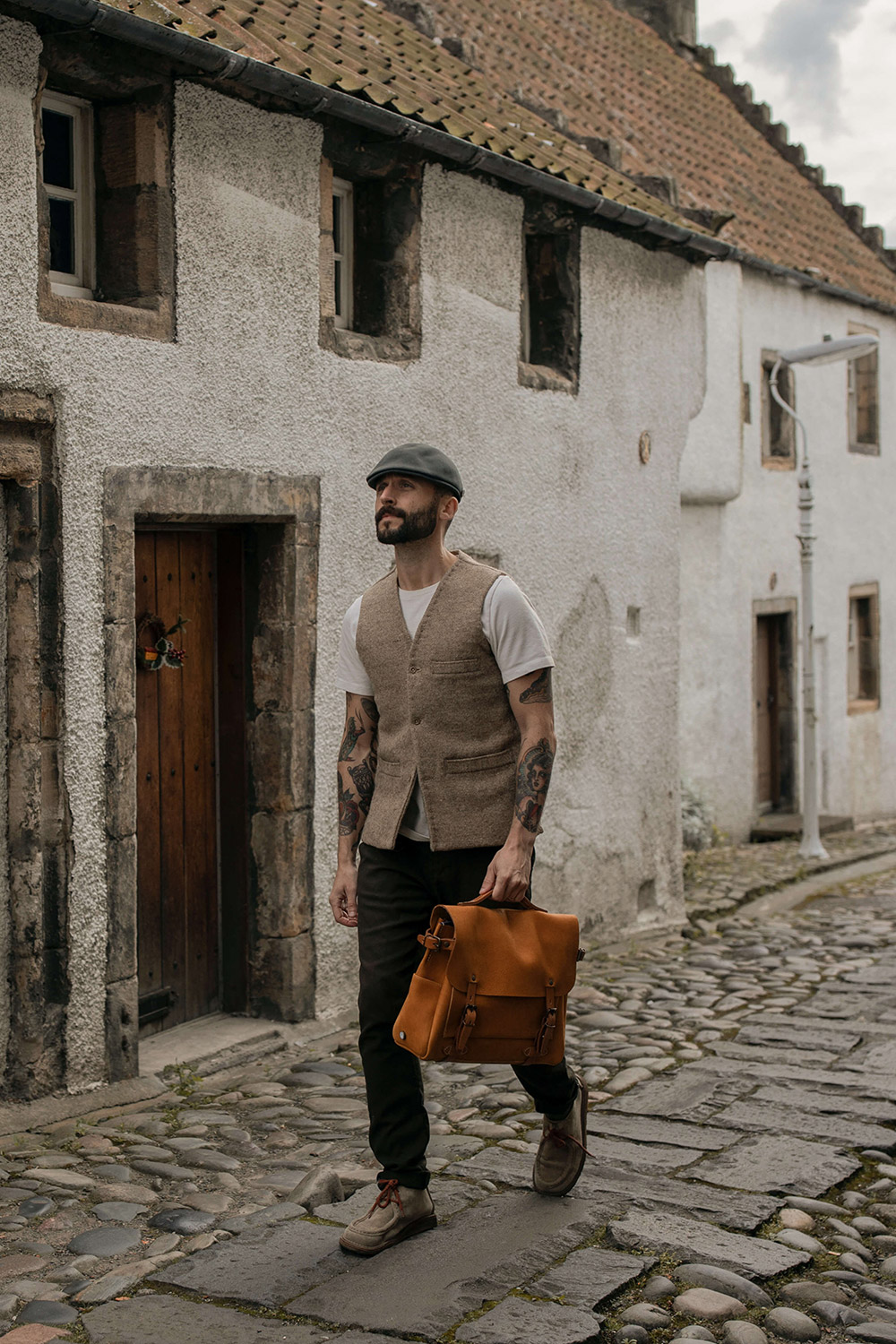 Un homme porte un cartable en cuir dans un village 