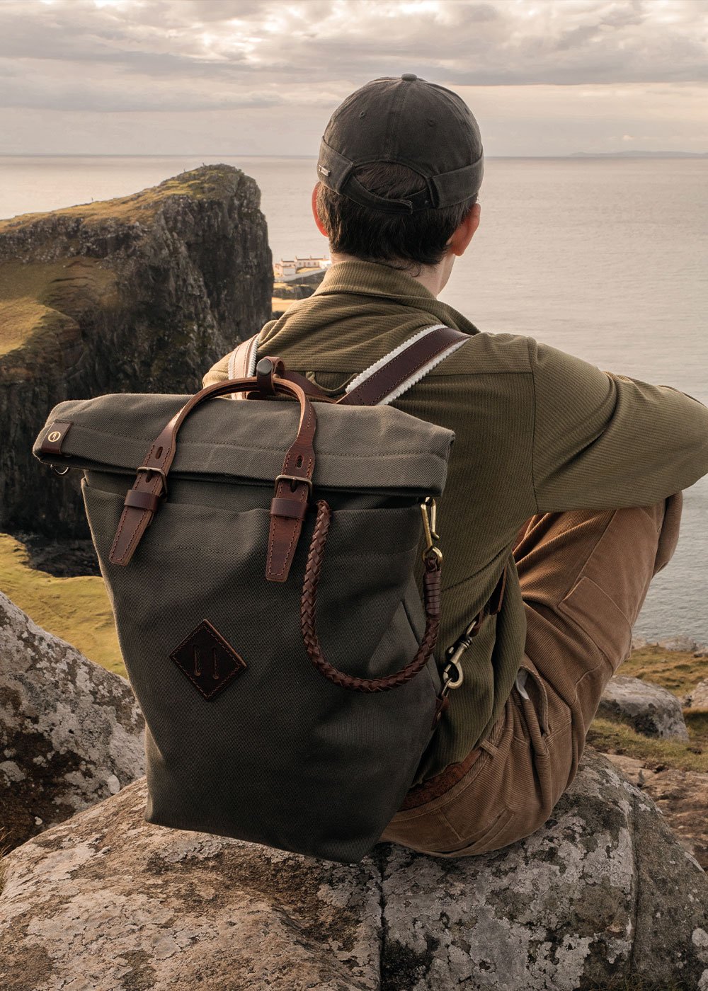 On the edge of a cliff, a man carries Woody's backpack