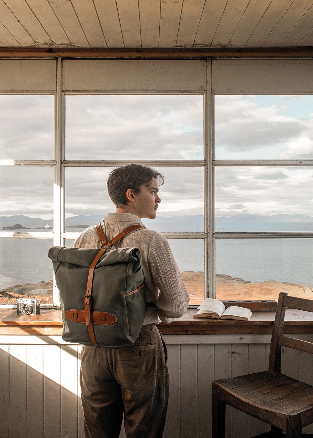 A man carries a canvas backpack into a lighthouse cabin