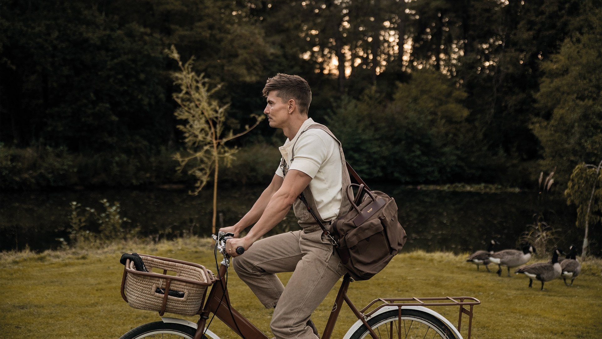 A man on a bicycle carries his computer bag on his shoulder