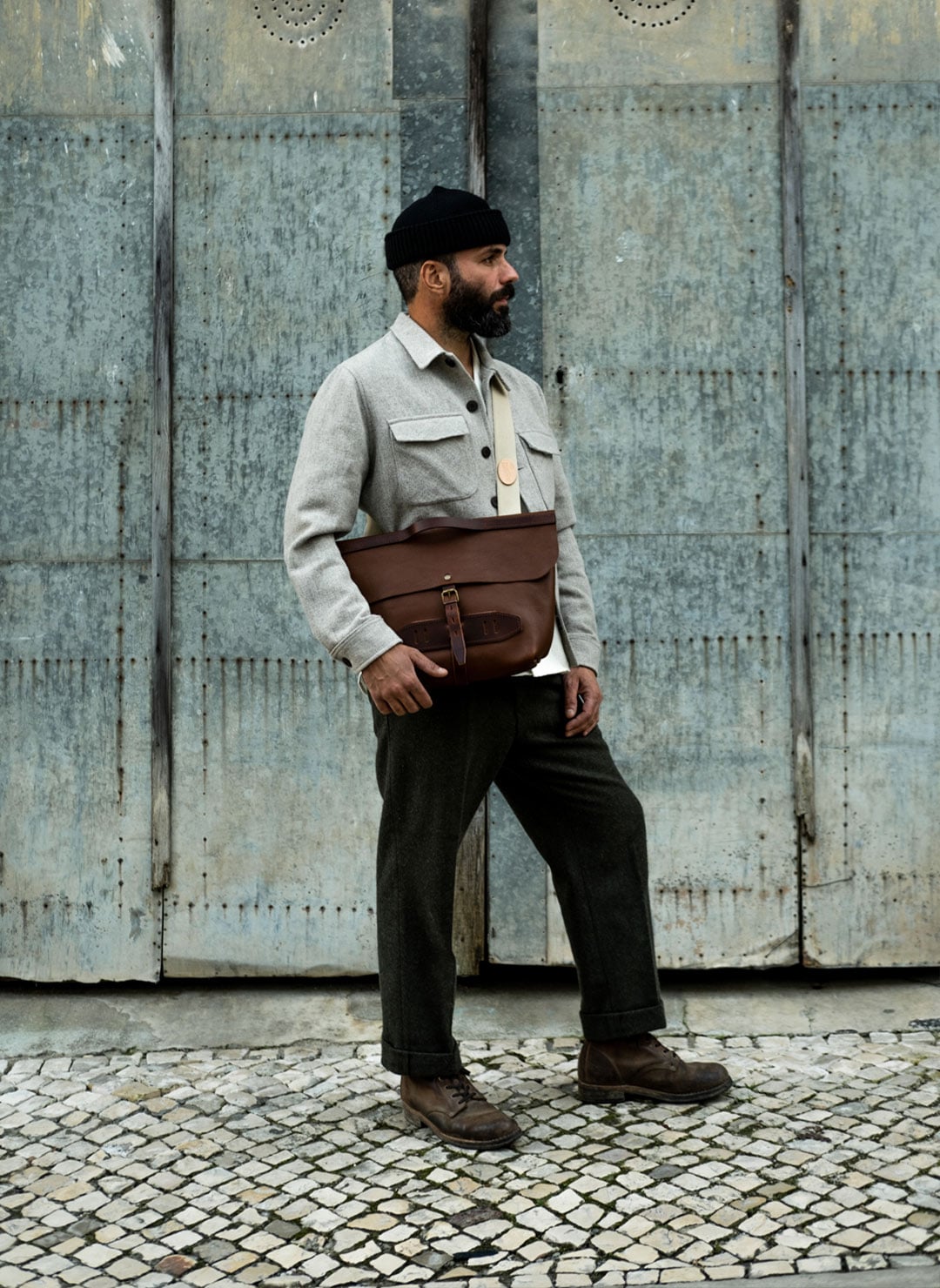 A man wears a Bleu de Chauffe messenger bag across his body