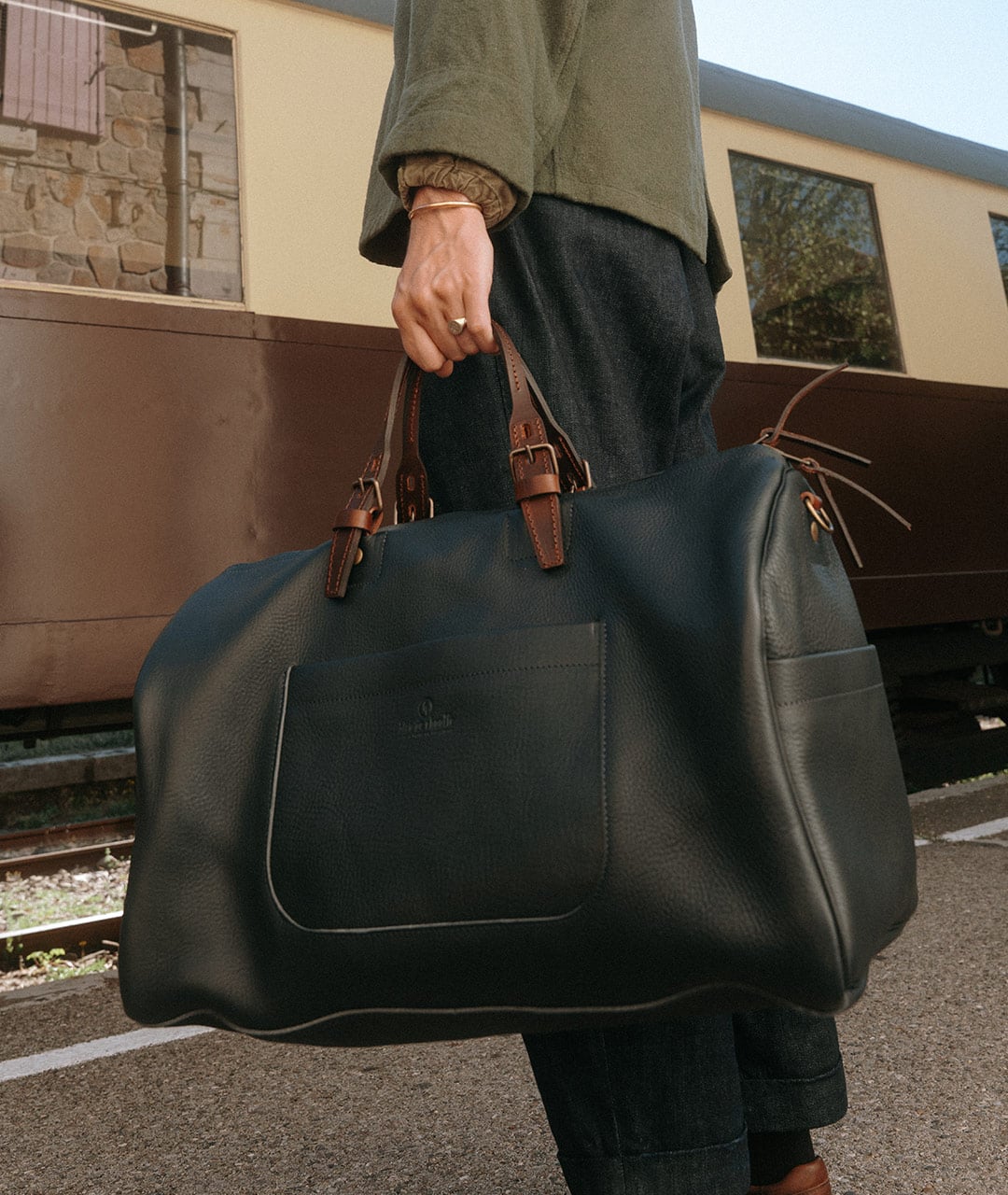 Personne portant un grand sac en cuir bleu marine &agrave; deux poign&eacute;es
