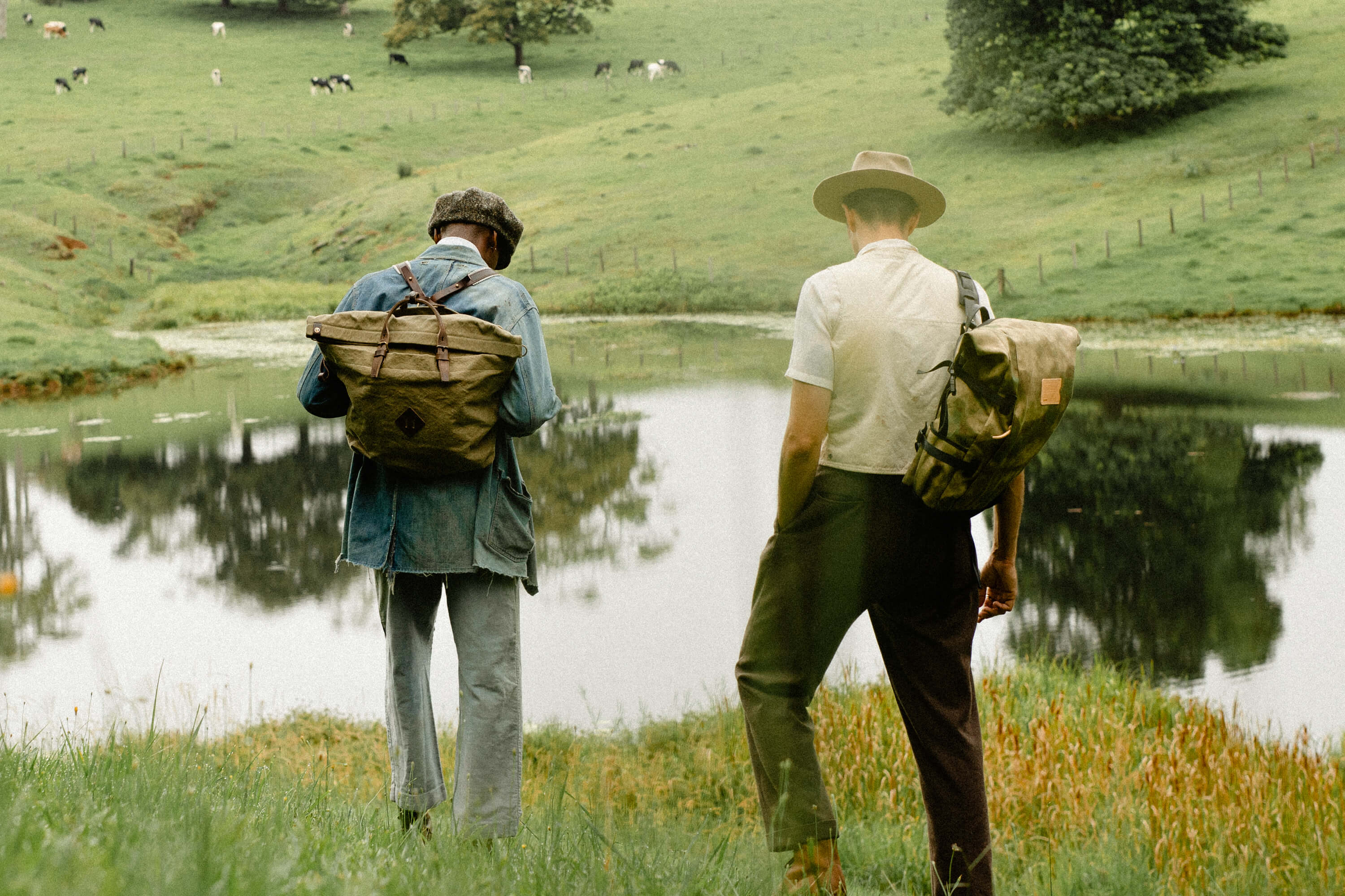 Two mens carries backpacks in front of a lake