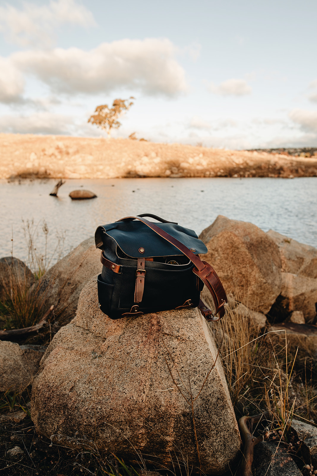 The Arles photo bag is on a rock in front of a lake