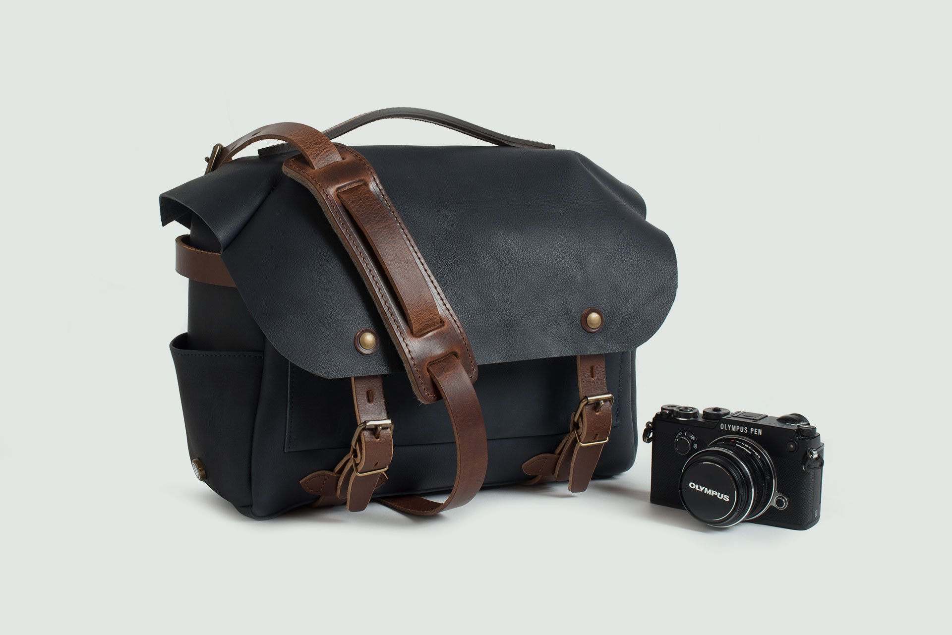 Bologna photo bag next to a camera on a plain grey background