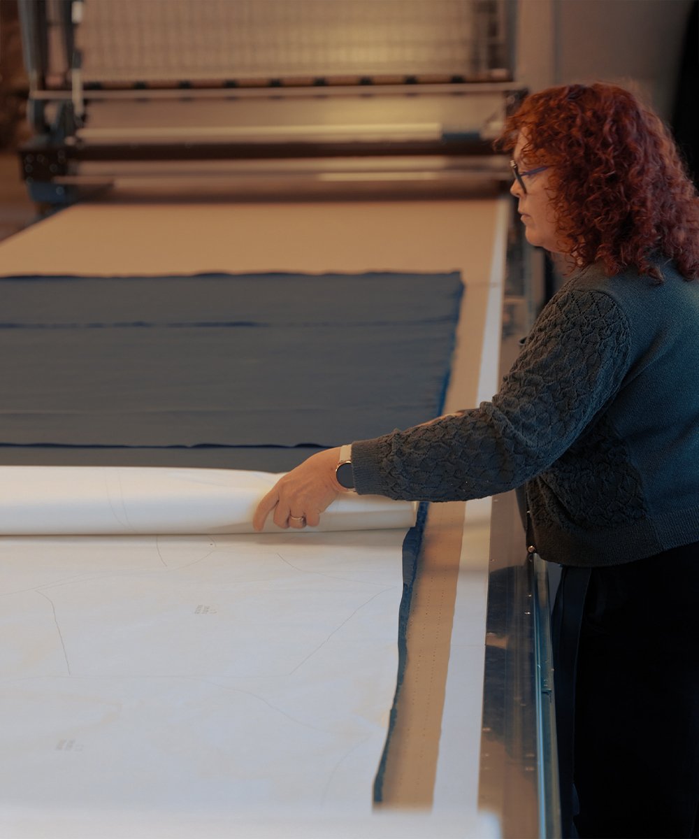 Ein Handwerker schneidet einen Stoff aus Bio-Baumwolle zu.