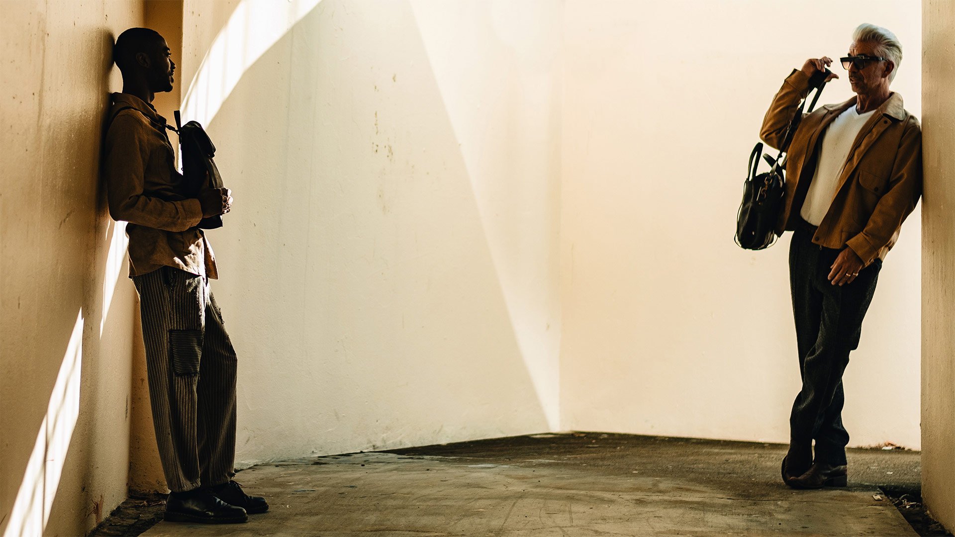 A man on the left is carrying the Puncho leather backpack and a man on the right is carrying the Report business bag.