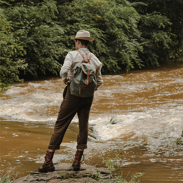 A man carries the Camp backpack to the river bank