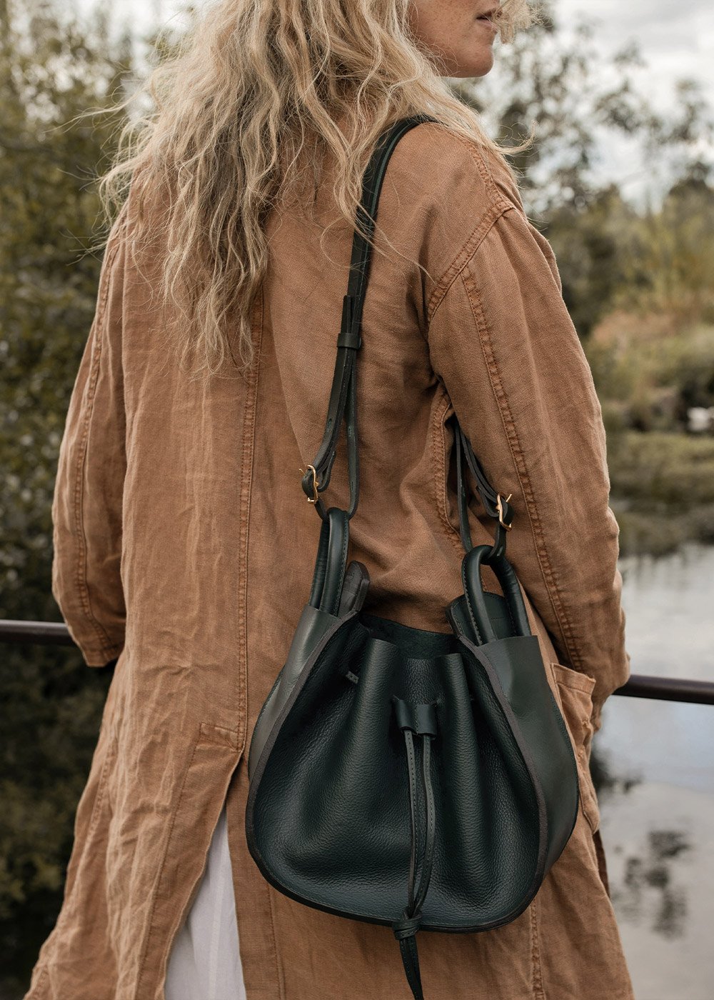 Une femme de dos porte un sac en cuir en bandouillère
