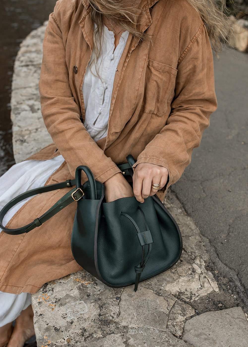 A woman is looking for something in her leather handbag